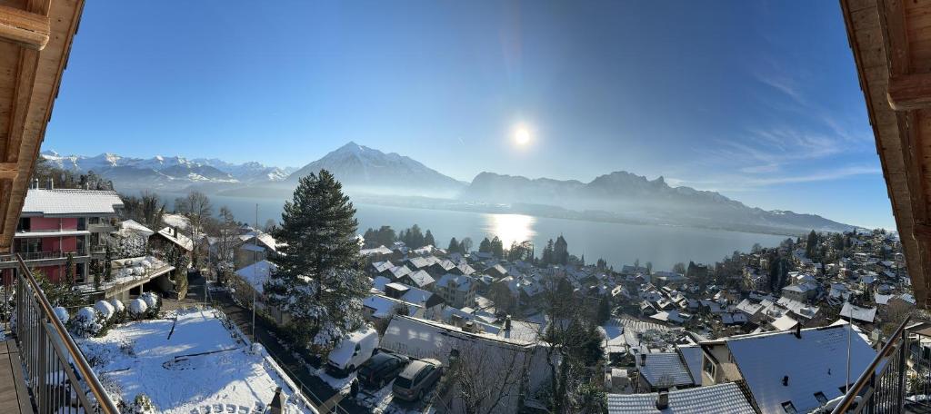 a town with snow covered buildings and a lake at Burgheim Siesta in Oberhofen am Thunersee