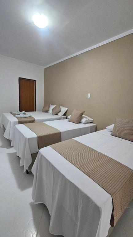 Un grupo de 4 camas en una habitación en Pousada Casa Bella, en Itaberaba