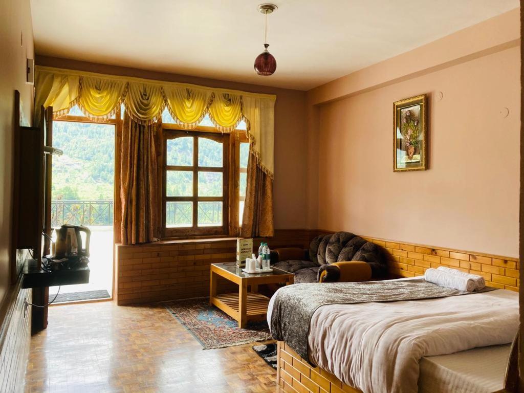 a bedroom with two beds and a couch and a window at hotel jupiter tamilnadu in Ooty