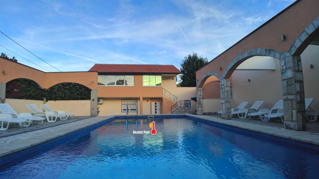 a swimming pool in front of a building with chairs at Holiday Home Rozić - Villa with private seasonal heated pool in Mostar