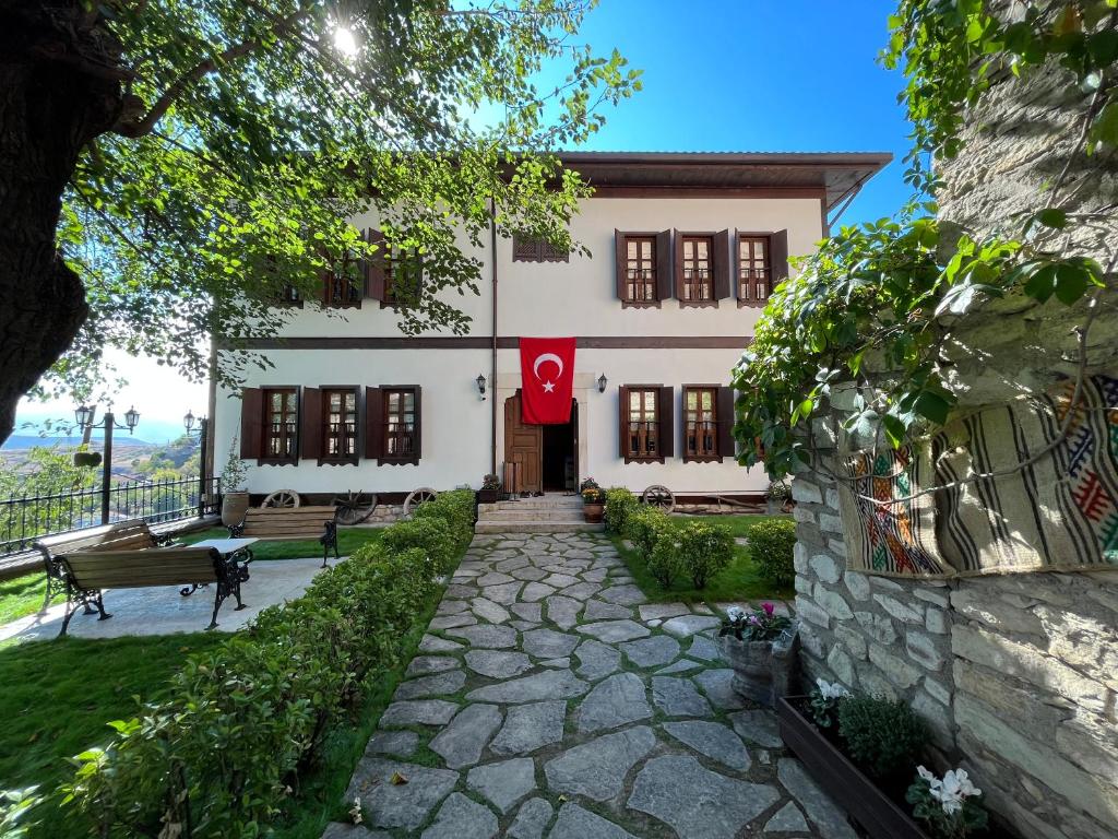 un gran edificio blanco con una bandera roja. en Leyla Hanım Konağı, en Safranbolu