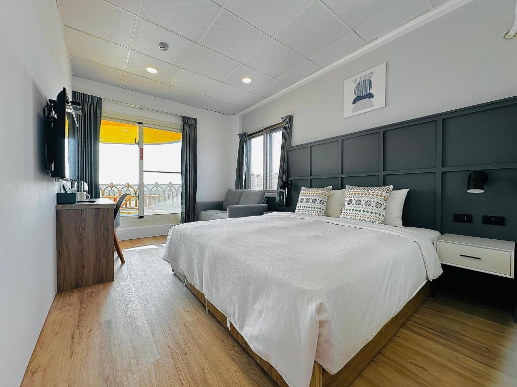 a bedroom with a large white bed with a black headboard at Qing Taoyuan Homestay in Hengchun South Gate