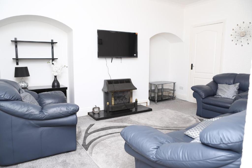 a living room with two blue couches and a tv at Beautiful and spacious 4- bedroom house in Sunderland in Pallion