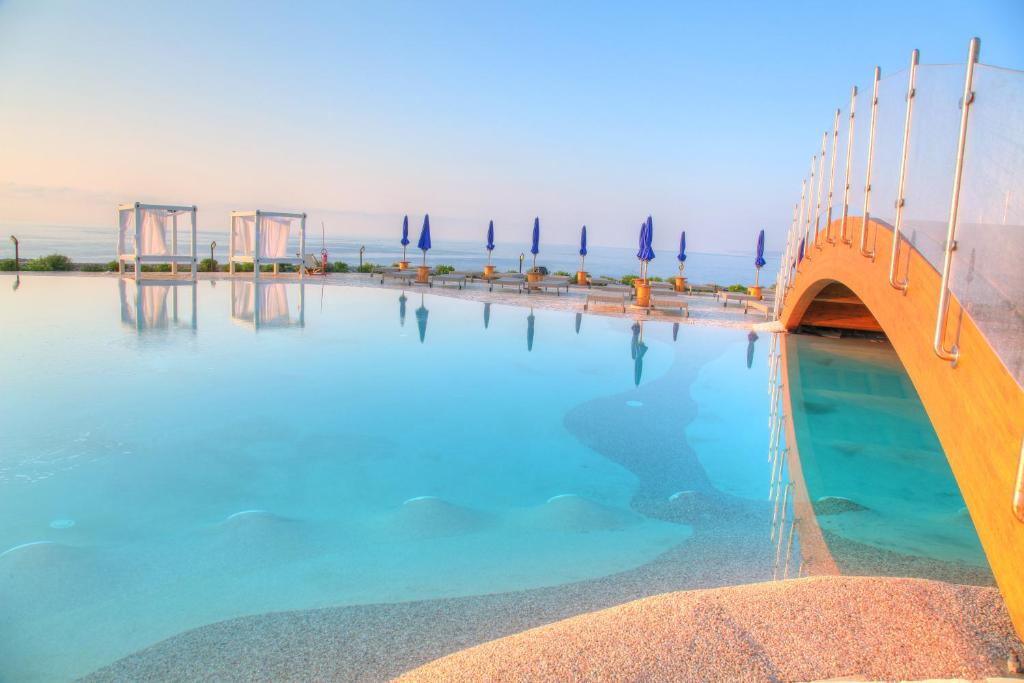 a swimming pool with blue water and a bridge at 19 Summer Suites in Santa Cesarea Terme