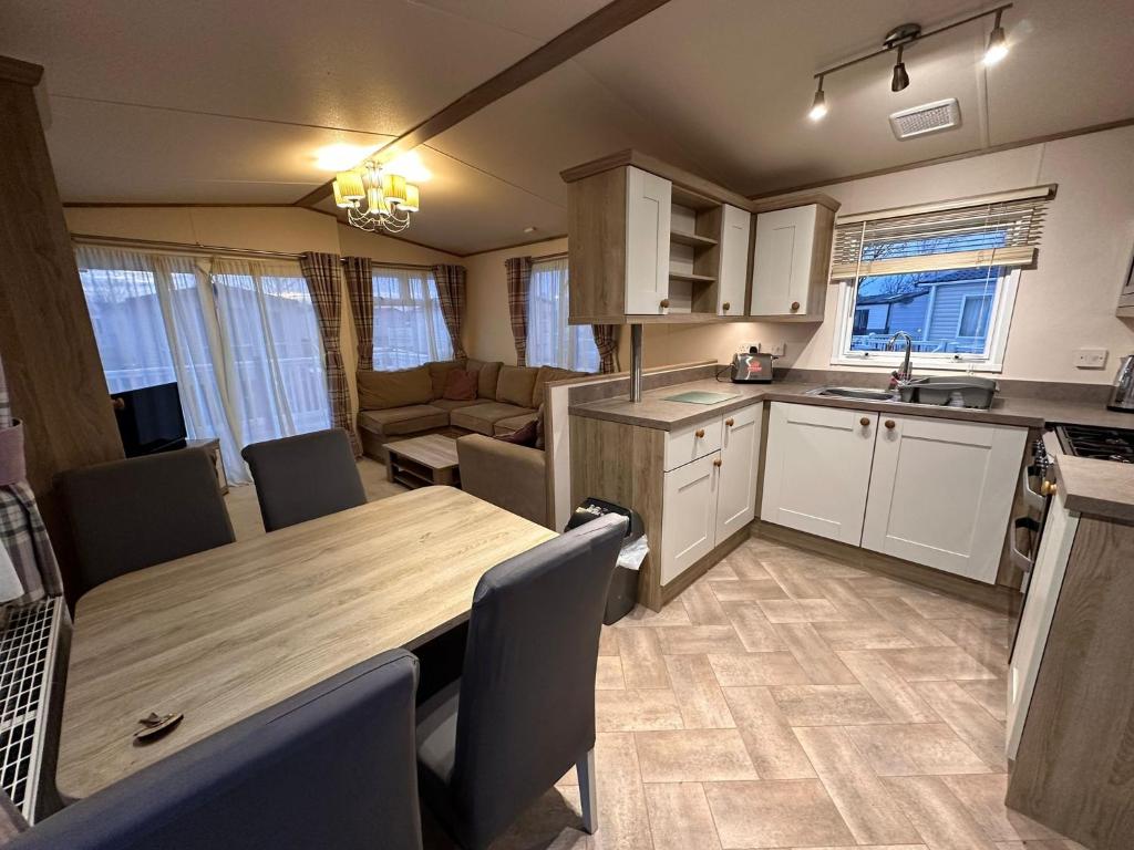 Caravana con cocina y sala de estar con mesa de madera. en Tattershall Lakes 6 berth with bath, en Tattershall