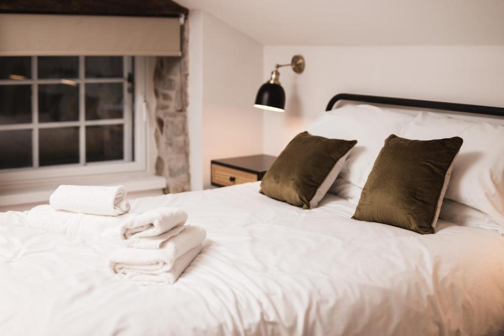 ein weißes Bett mit Handtüchern und einem Fenster in der Unterkunft Bankers Room + Kitchenette in Chapel en le Frith
