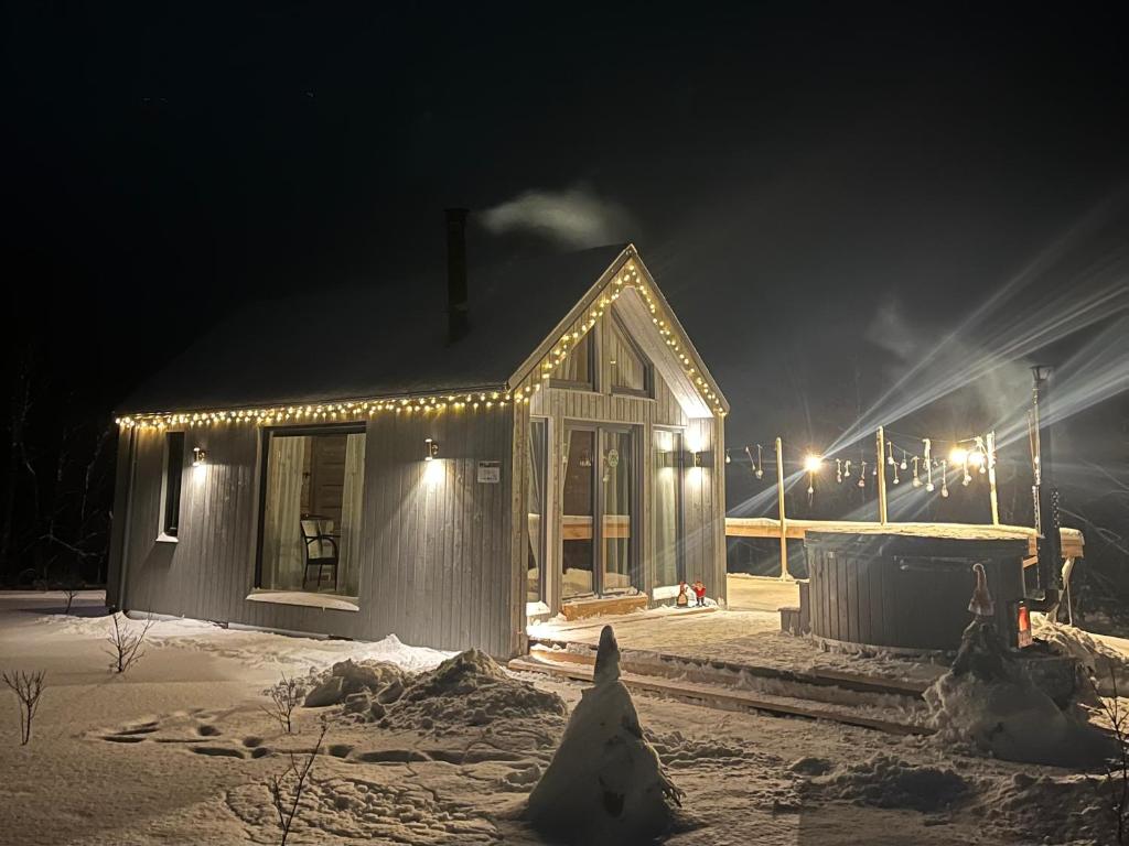 dom pokryty światłami w śniegu w nocy w obiekcie Smiltsērkšķu namiņš 