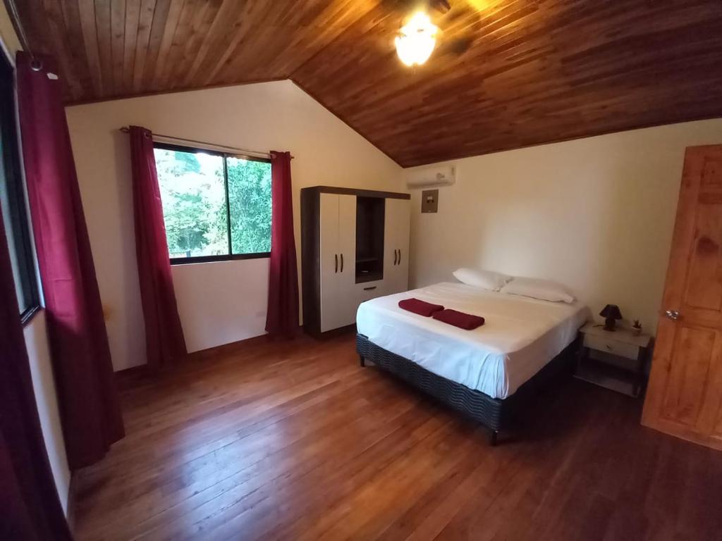 Schlafzimmer mit einem Bett und Holzboden in der Unterkunft Aura Bungalow in Tamarindo