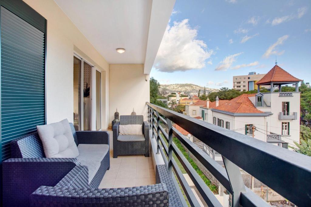 uma varanda com cadeiras e vista para a cidade em Apartamento Caires no Funchal