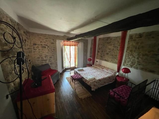 a bedroom with a bed and a chair and a window at Ca' Rosmunda in Bagnone