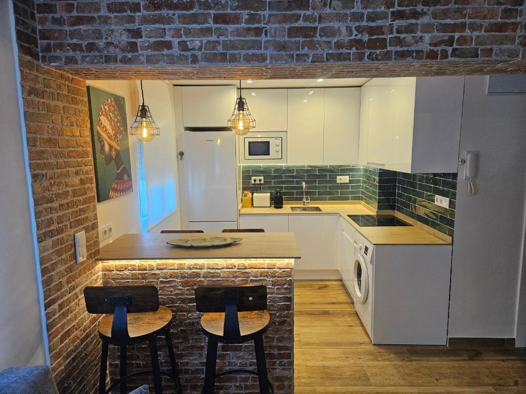 a kitchen with a counter and two stools in it at apartamento a estrenar junto al Sardinero in Santander