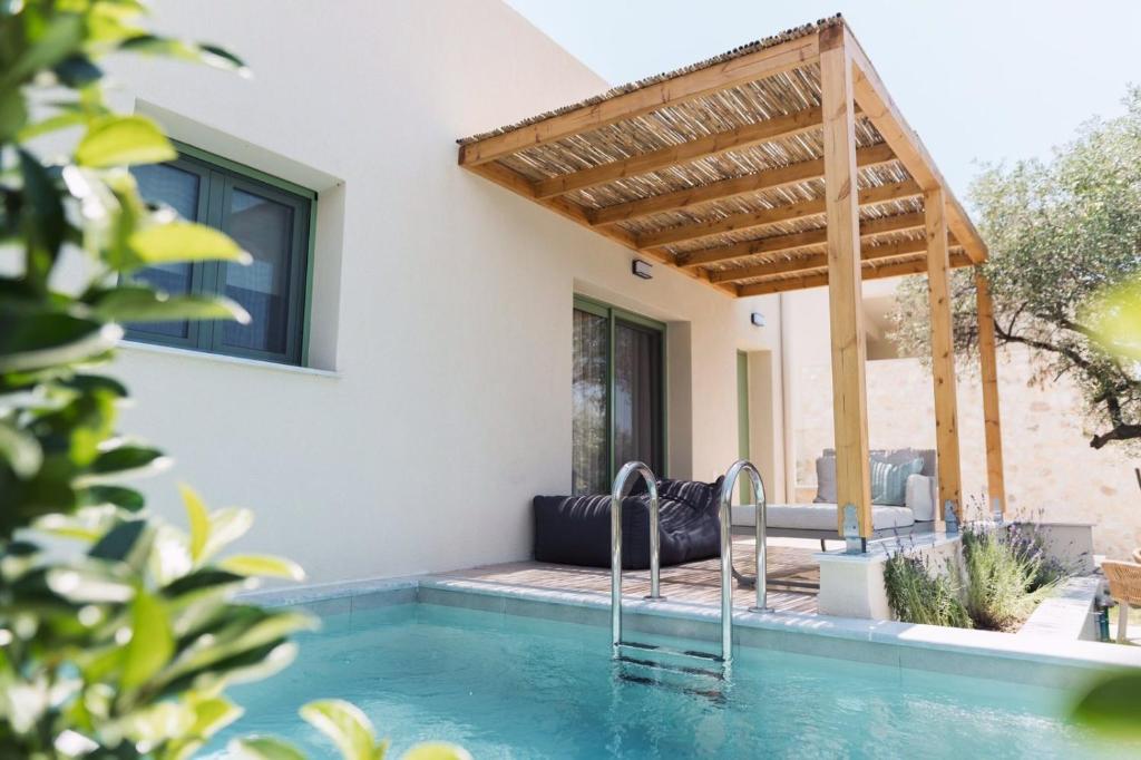 a house with a swimming pool with a wooden pergola at Magnolia Villas Potos Thassos in Potos