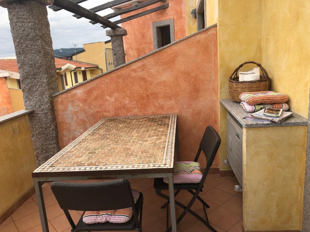 een tafel en stoelen op een balkon met een tafel en een mand bij Appartamenti Perego in Castelsardo
