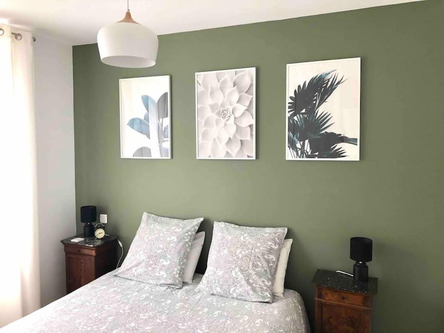 une chambre avec un lit avec quatre tableaux au mur dans l'établissement T2 sur jardin, au cœur de Luchon, à Luchon