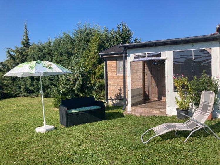 a chair and an umbrella in a yard with a house at NEUTRINO VENDÉGHÁZ in Zánka