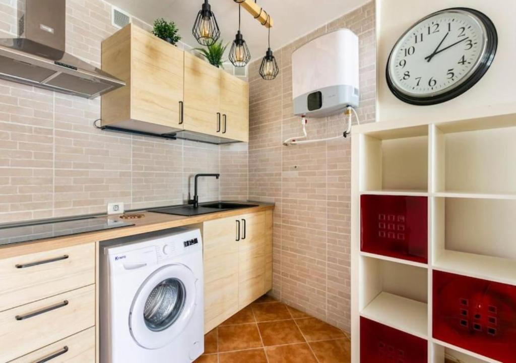 a kitchen with a washing machine and a clock on the wall at Cosy Apartment in Los Cristianos 5min to the ocean in Los Cristianos