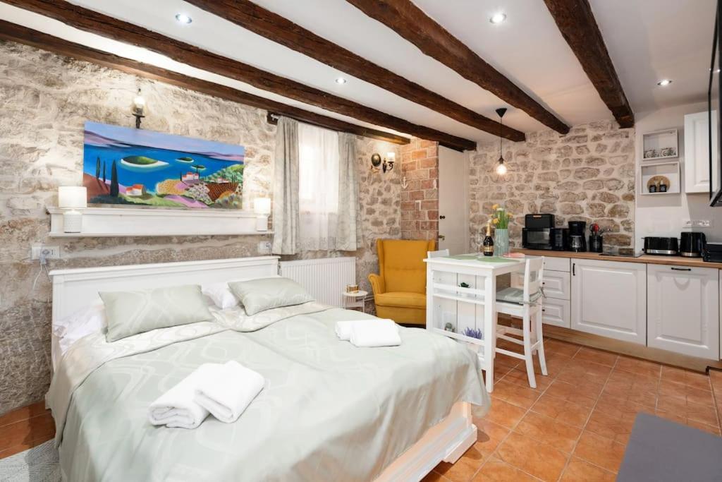a bedroom with a white bed and a kitchen at Pinna by Briskva in Vrsar