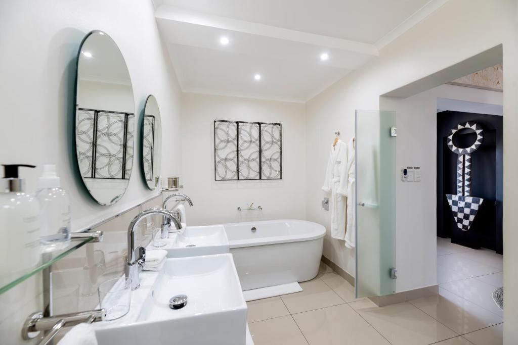 a white bathroom with a tub and a sink at THEBLOEM Guest Suites by Knysna Paradise Collection in Knysna