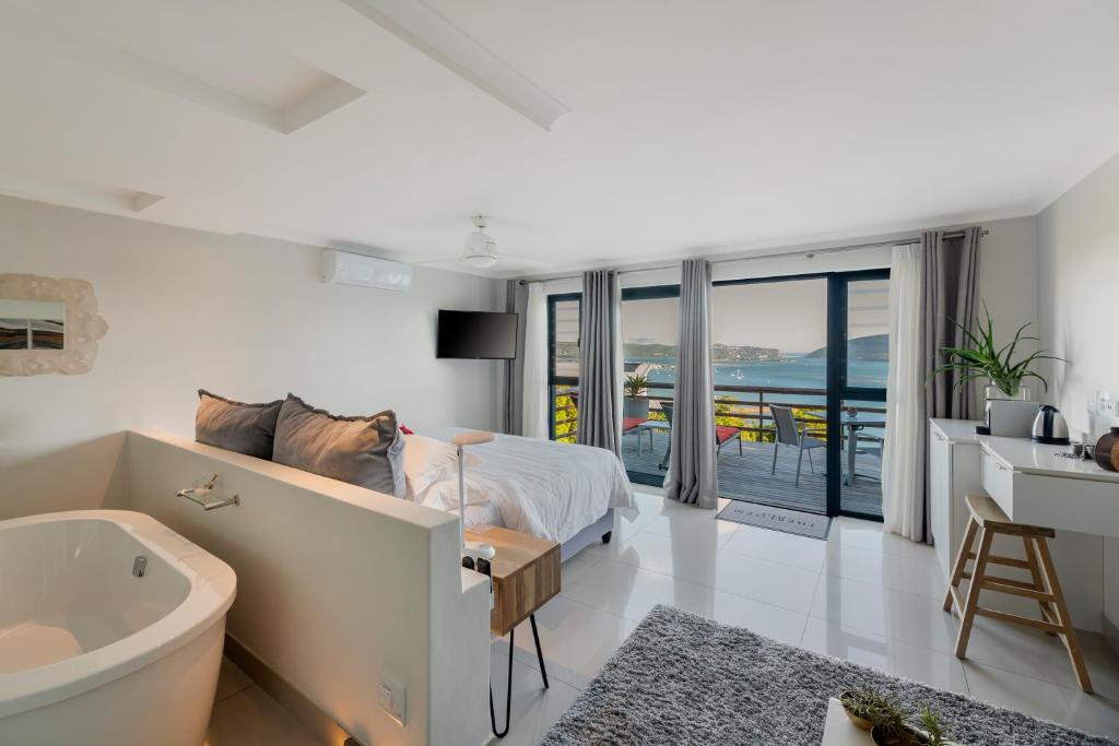 a bedroom with a tub and a bed and a sink at THEBLOEM Guest Suites by Knysna Paradise Collection in Knysna