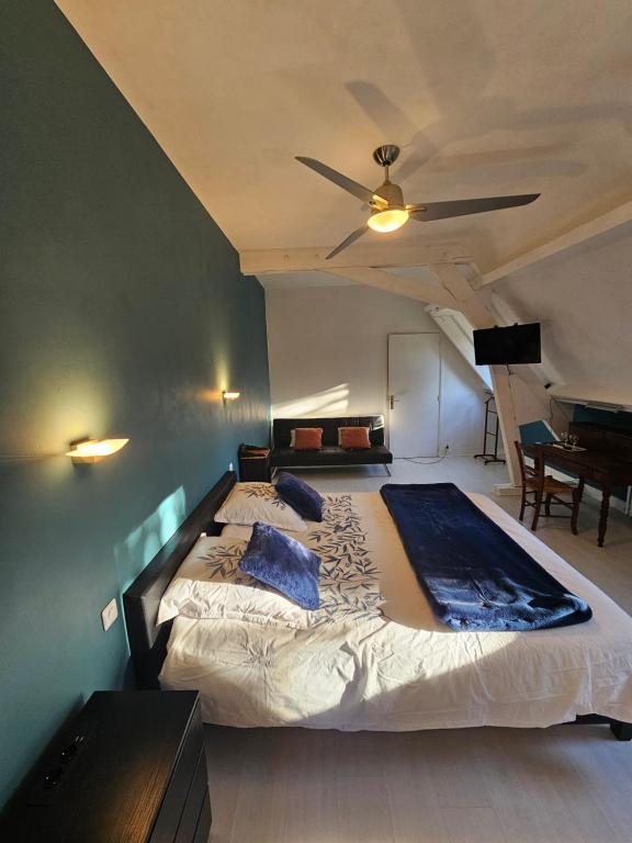 a bedroom with a large bed with a ceiling fan at La demeure aux Pins in Lourdes