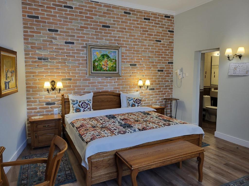 a bedroom with a large bed with a brick wall at Hotel Odeon in Plovdiv