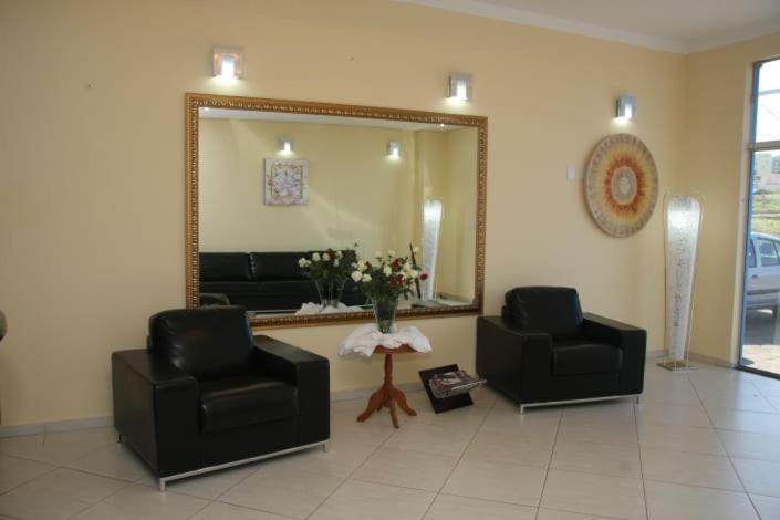 a living room with two chairs and a mirror at Hotel 5 minutos da Agrishow in Ribeirão Preto