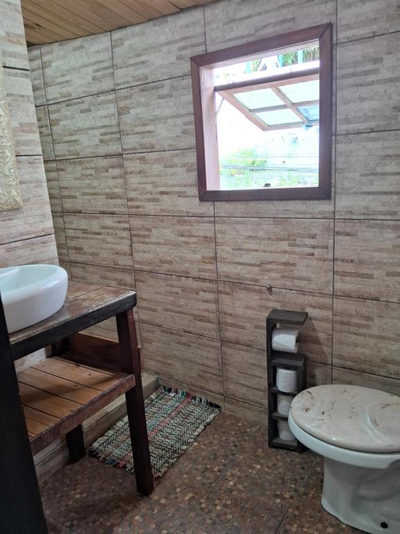 a bathroom with a toilet and a sink and a window at Pousada Marambaia Café in Barra de Guaratiba