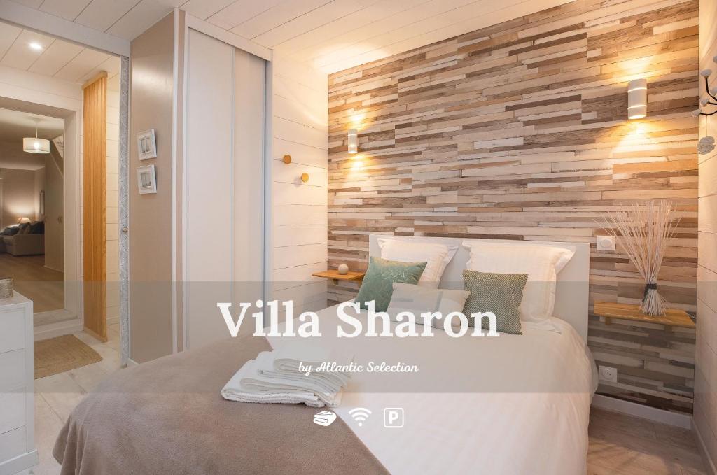 カップブルトンにあるAtlantic Selection - Un séjour à la Villa Sharon avec terrasse et parkingの木のアクセントの壁とベッドが備わるベッドルーム1室が備わります。