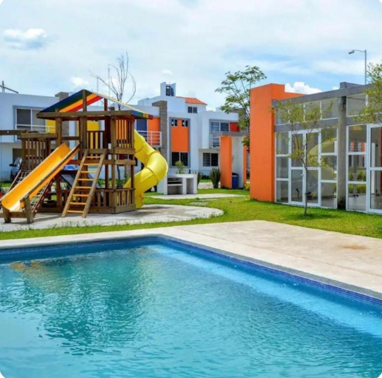 a pool with a slide and a playground next to a building at Alojamiento privado con seguridad in Tepic