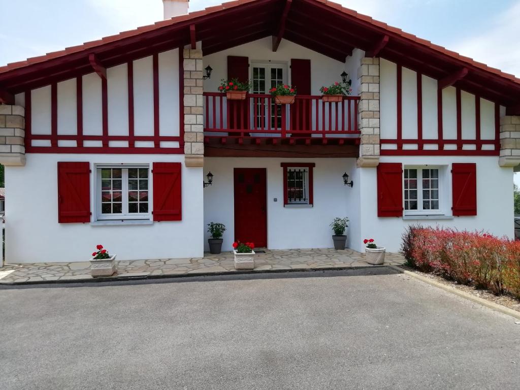 a white house with red doors and windows at Chambre ERREGUINA in Hasparren