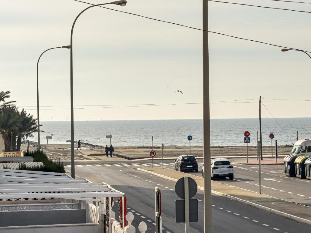 una calle con coches conduciendo por una carretera junto al océano en Casa ”Playa”, en Santa Pola