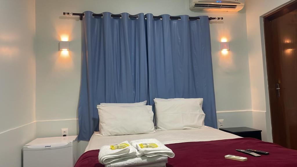 - une chambre avec un lit doté d'un rideau bleu dans l'établissement POUSADA DA MAGA, à Chapada dos Guimarães