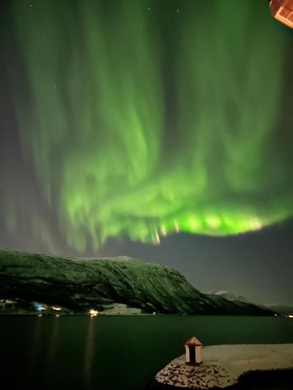aurore sur une masse d'eau avec un bâtiment dans l'établissement Malangen Arctic Sealodge Cabin 10, à Meistervik