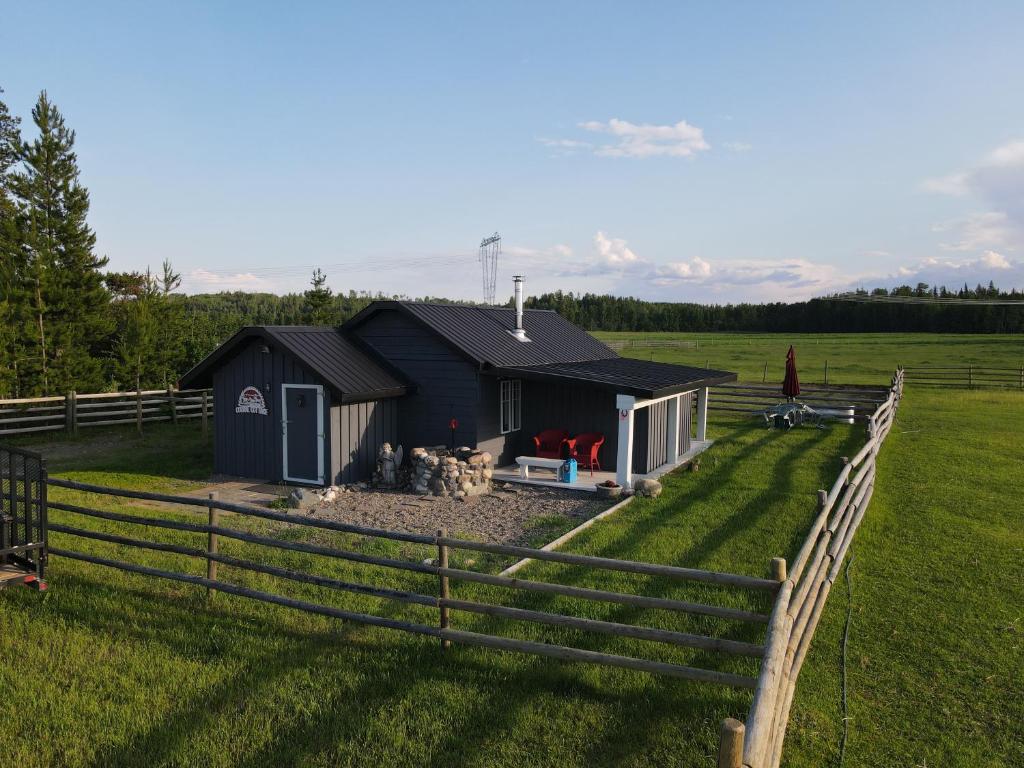 a black shed in a field next to a fence at Woodhouse Cottages And Ranch in Prince George