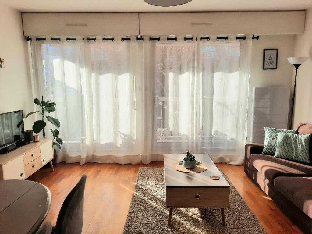 een woonkamer met een bank en een salontafel bij Beautiful & cosy apartment - La Défense in Courbevoie