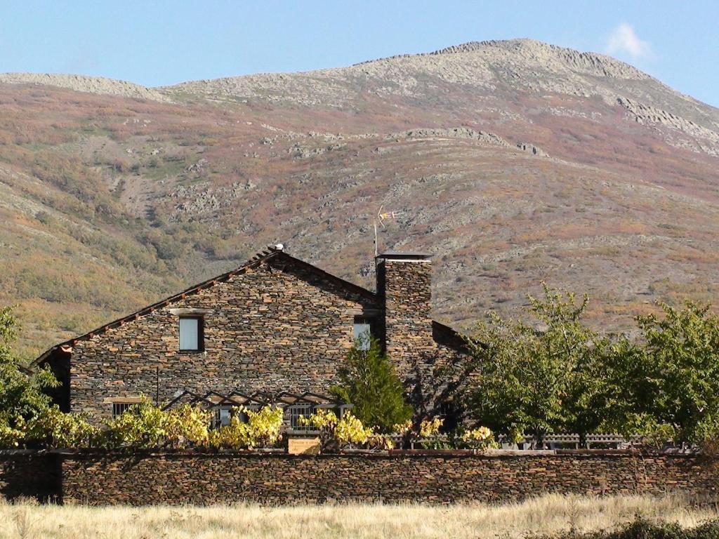 a stone house in front of a mountain at Cerezas y Miel in Majaelrayo
