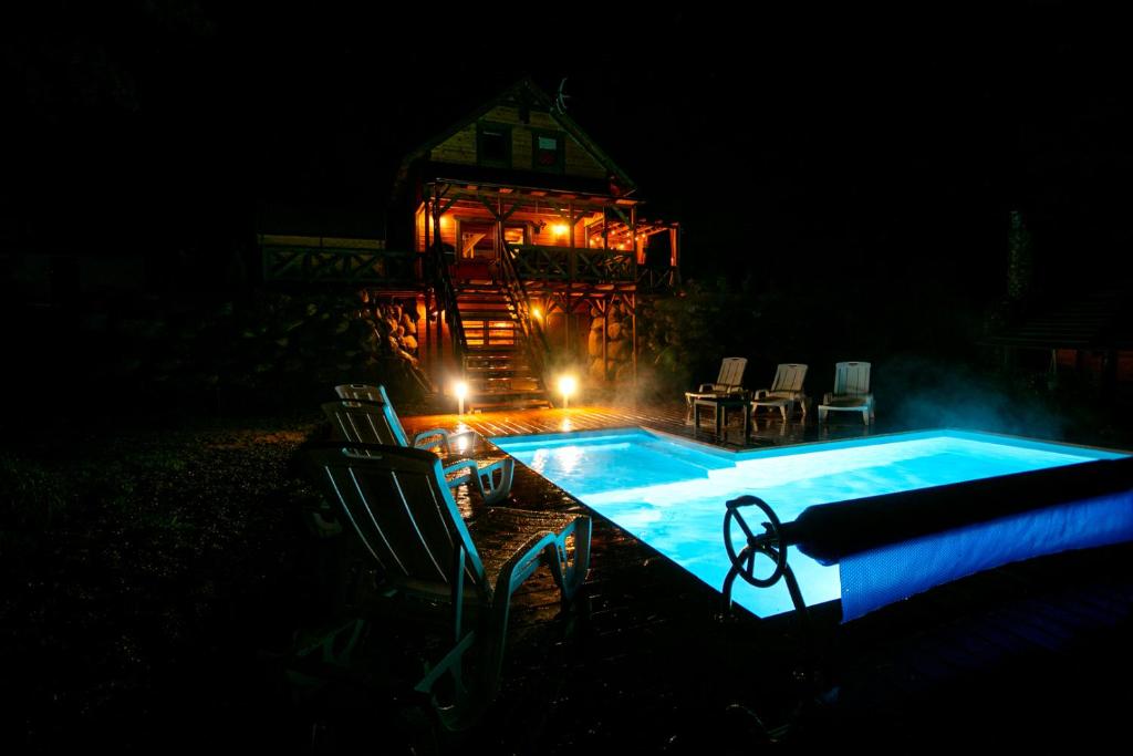 a swimming pool at night with a gazebo at Domek całoroczny RYSIÓWKA na Kaszubach z basenem banią sauną bilardem na wyłączność - Ostrowite Leśna Dolina in Sulęczyno