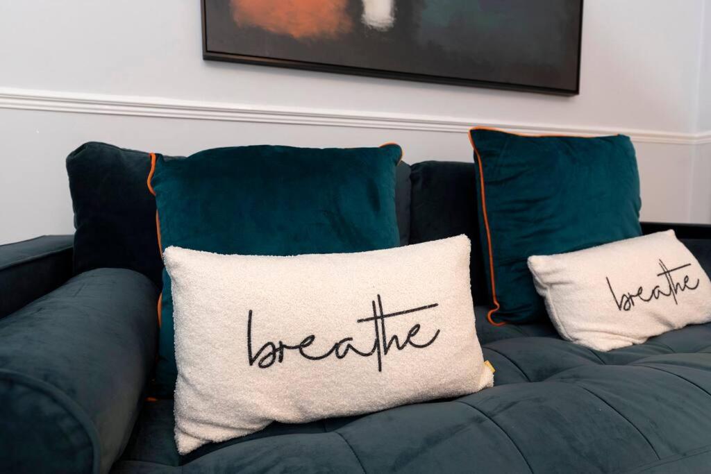 Sofá azul con dos almohadas con palabras para respirar en Carrick House, en Hartlepool