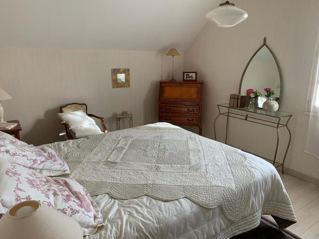 1 dormitorio con cama, tocador y espejo en Capucine, en Noyen-sur-Sarthe