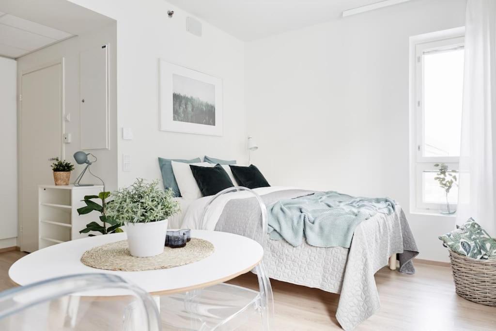 a white bedroom with a bed and a table at Beautiful apartment in the center of Tampere in Tampere