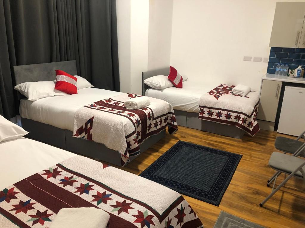 a room with two beds with red and white blankets at Callcote road Hotel in London