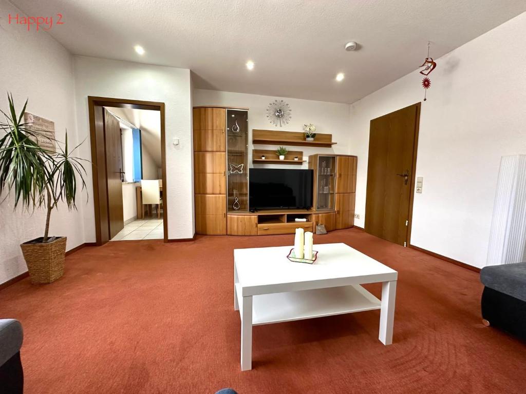 a living room with a white table and a tv at Apartment Happy in Homburg