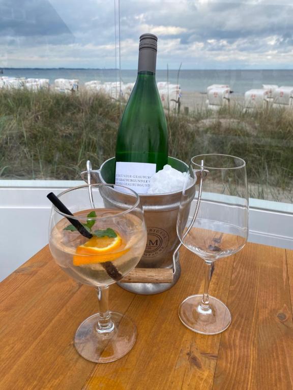 a bottle of wine and two glasses on a table at Charmante Ferienwohnung in Scharbeutz -Ihr perfektes Zuhause am Meer! Terasse, Parken & Strand! W1 in Scharbeutz
