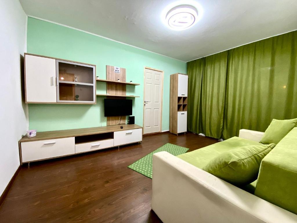 a living room with a couch and a green wall at Twins Apartments 2 in Ploieşti