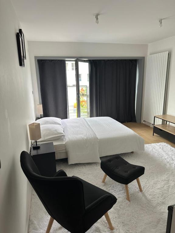 - une chambre avec un lit blanc et une chaise noire dans l'établissement New Upscale 1 bedroom Apartment, à Paris