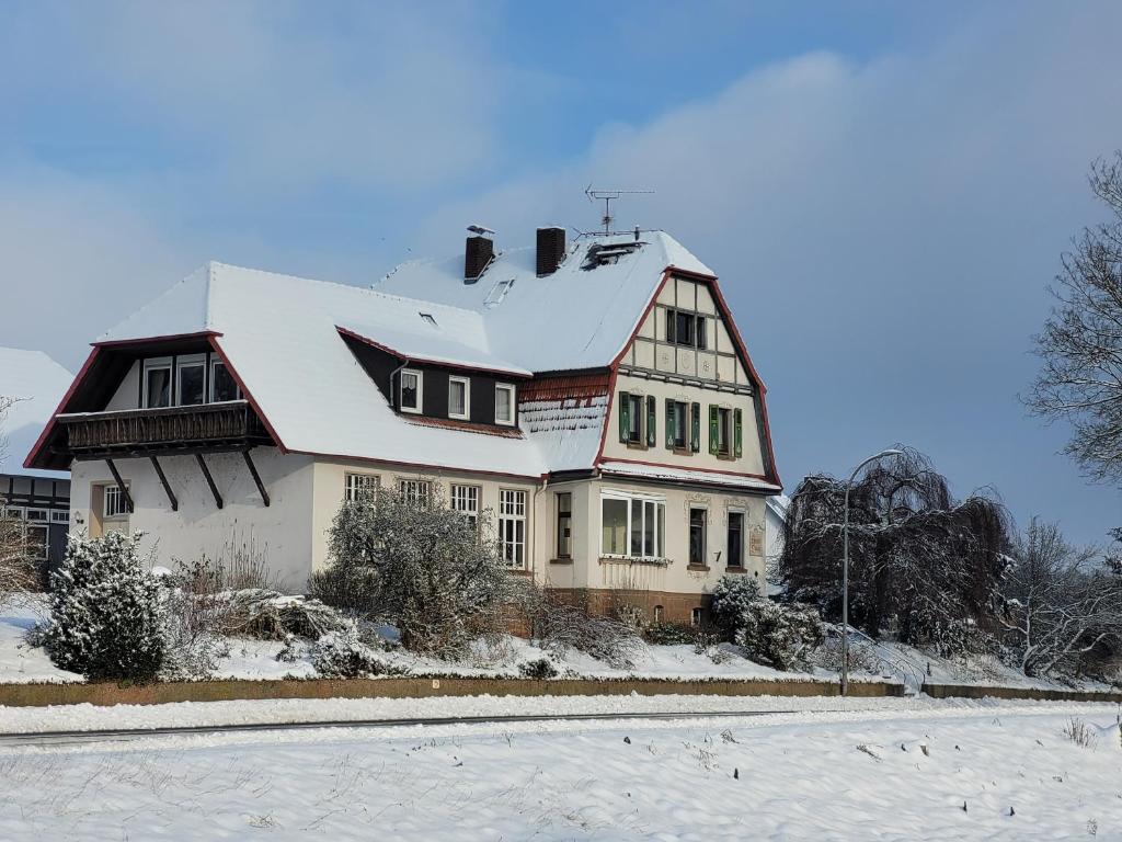 een groot huis met een met sneeuw bedekt dak bij Alte Dorfschule Kohlgrund in Bad Arolsen