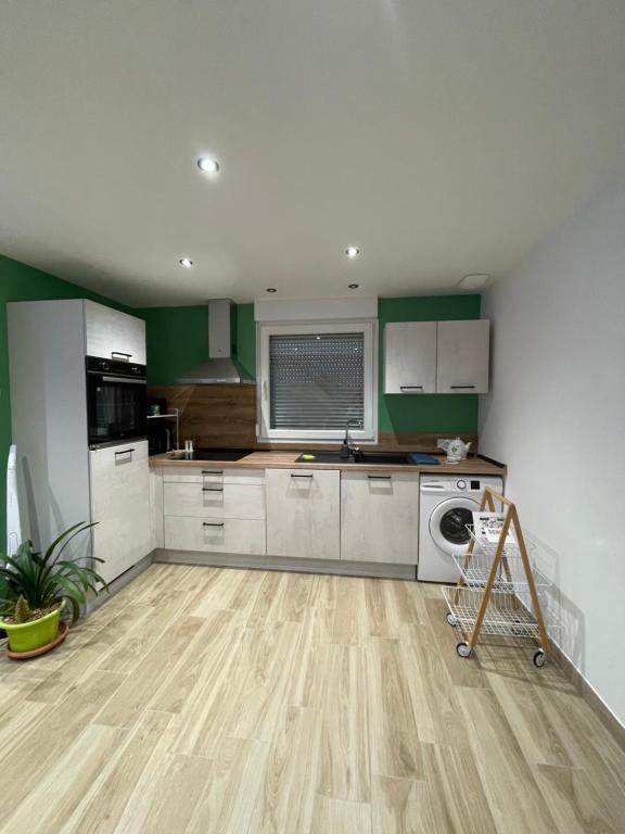 a kitchen with green and white cabinets and a wooden floor at Chez Gigi et Malou - gîte Brimbelle in Champ-le-Duc
