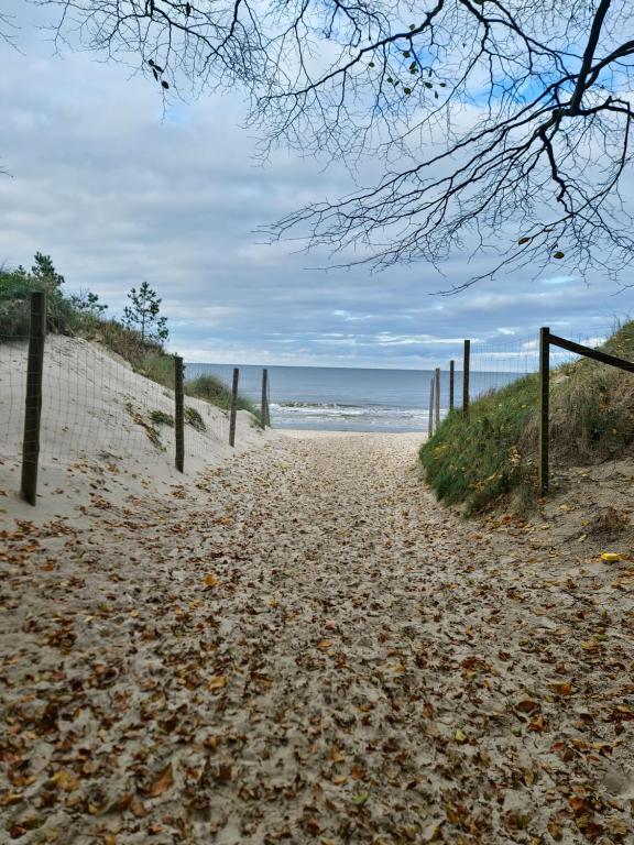 a sandy path to the beach with a fence at MyHome Sunset Grzybowo in Grzybowo