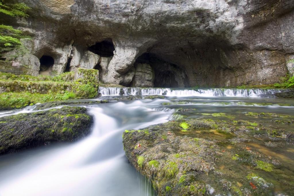 une rivière dans une grotte avec une cascade dans l'établissement A l'Ombre du Château, à Nans-sous-Sainte-Anne