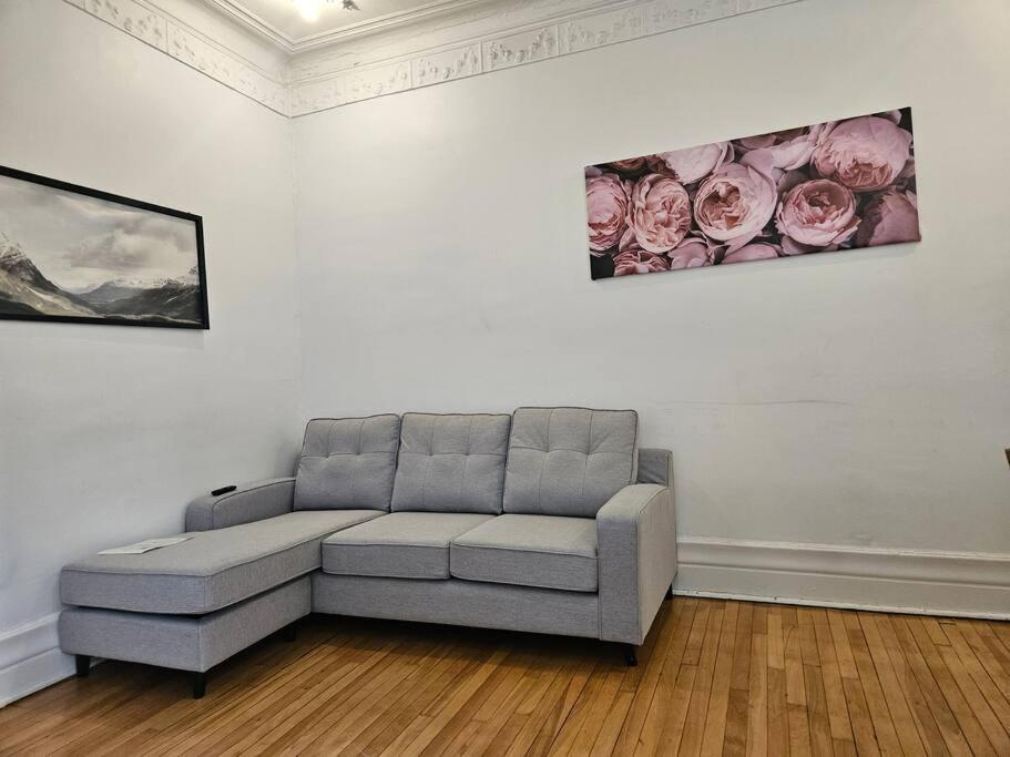 a couch in a room with two paintings on the wall at Mona Bella Beautiful Home In Mile End in Montréal